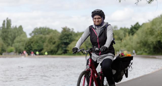 A person is riding a red bike along the edge of a lake