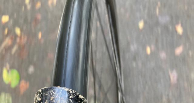 A close-up of a bike wheel from  the top as the bike is being ridden along a path. There's mud on the mudguard