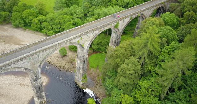 Two cyclists ride over a viaduct